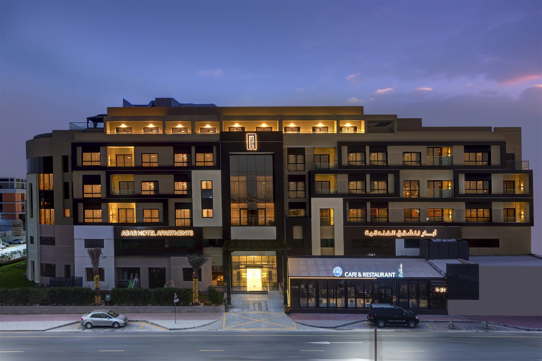 Abar Hotel Apartments at dusk, with the Gul Café & Restaurant entrance lit up