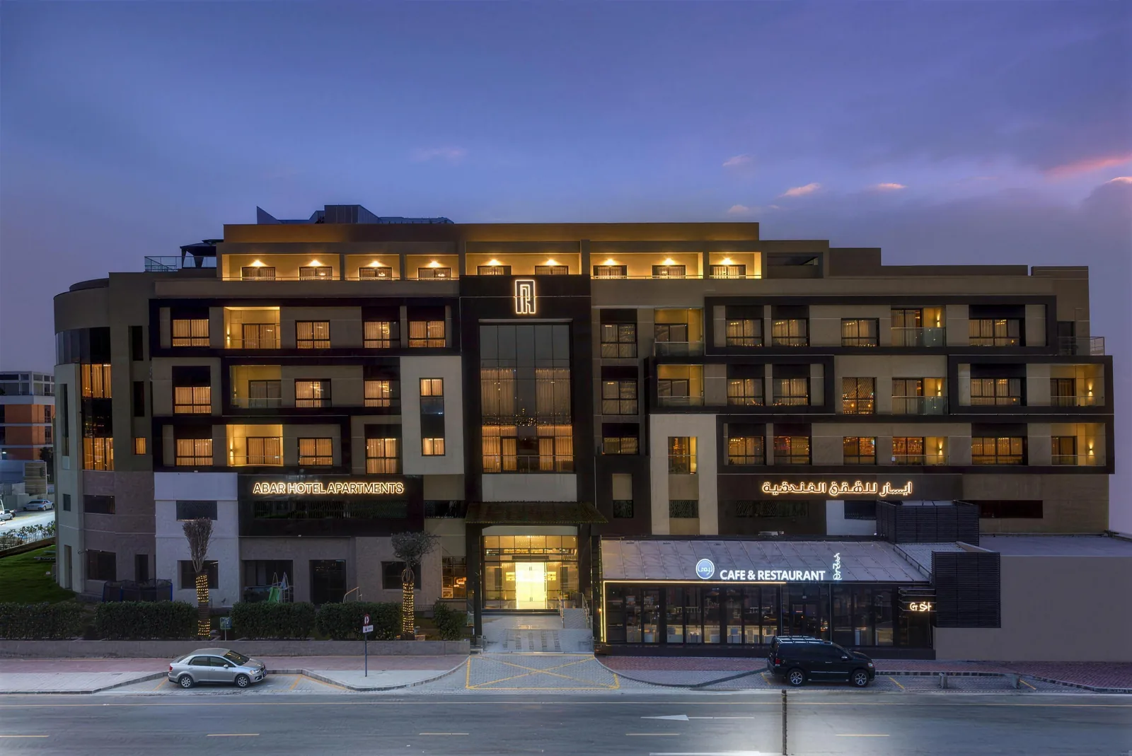 Abar Hotel Apartments at dusk, with the Gul Cafe & Restaurant entrance lit up